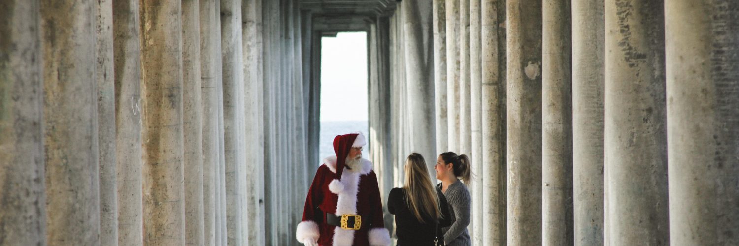 Two women meet Santa Clause under the dock at the beach for a CovidSafe Holiday