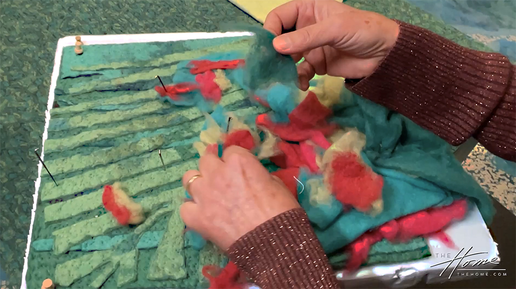 Liora Manné demonstrates her Lamontage® needle-punching process by placing fiber on design