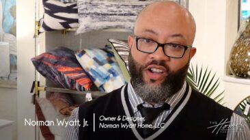 Norman Wyatt Home Lifestyle Collection with StyleCraft showroom, black man with dark beard and black-rimmed glasses in black and white vest, colorful throw pillows in background. Text: Norman Wyatt, Jr., Owner & Designer, Norman Wyatt Home, LLC