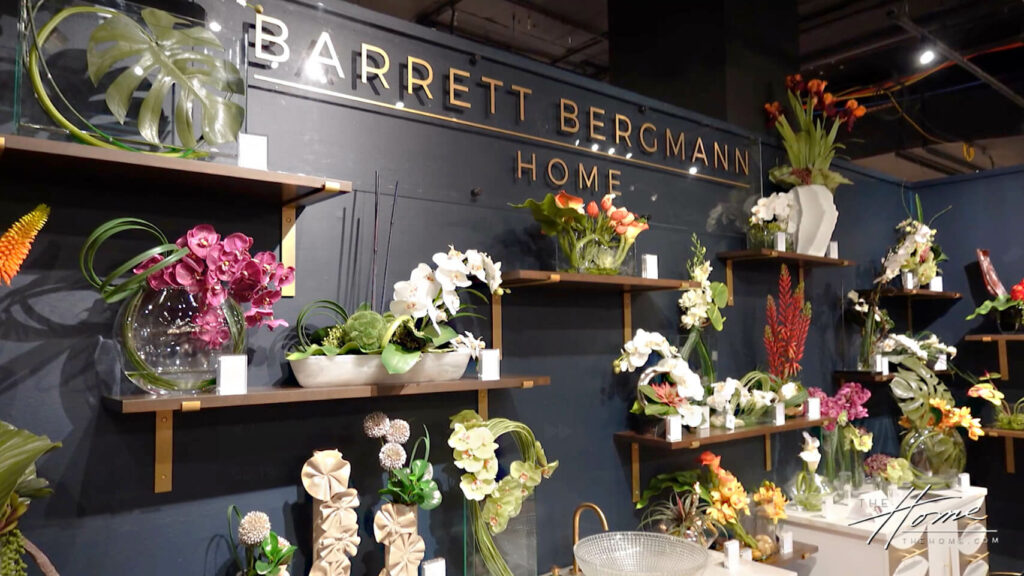 Image: Barrett Bergmann Home showroom with dark gray walls and brightly colored floral arrangements