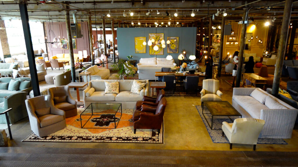 Image: large furniture showroom in old warehouse filled with sofas, rugs, coffee tables, lighting