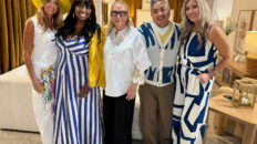 Image: group of 4 women and one man, all wearing white and blue outfits in a furniture showroom