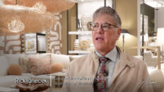 Image: man with glasses, tan jacket, tie, checkered shirt in furniture showroom, peach pillows and white couch. Text: Rick Janecek, Creative Director/Brand Manager, Revelation by Uttermost