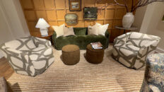 Image: Norwalk Furniture showroom with velvet green modern couch, cream pillows, 2 abstract fabric swivel chairs, tan rug, brown pouf ottomans