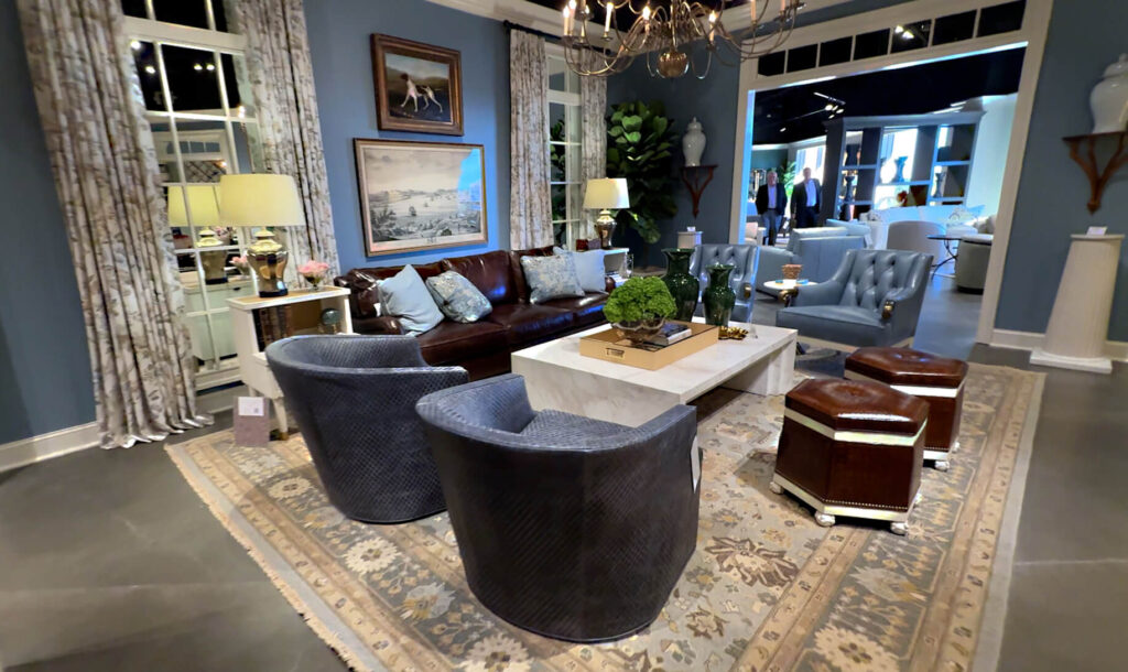 Corey Damen Jenkins living room furniture collection with 2 blue swivel chairs, dark brown leather sofa, hexagon shaped brown leather ottomans, white stone coffeetable, tan patterned rug, blue Doxon chair
