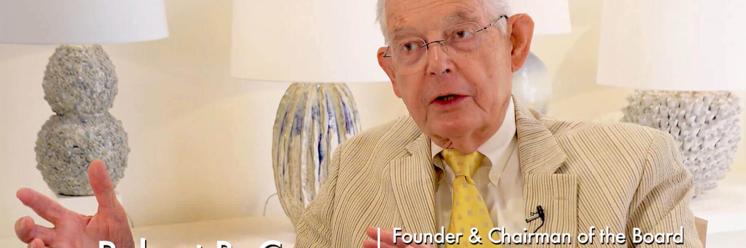 Currey & Company showroom with older man with white hair expressing with hands, wearing yellow and tan seersucker suit jacket, art lamps in background. Text: Robert B. Currey Founder & Chairman of the Board, Currey & Company, Part 2 of 2