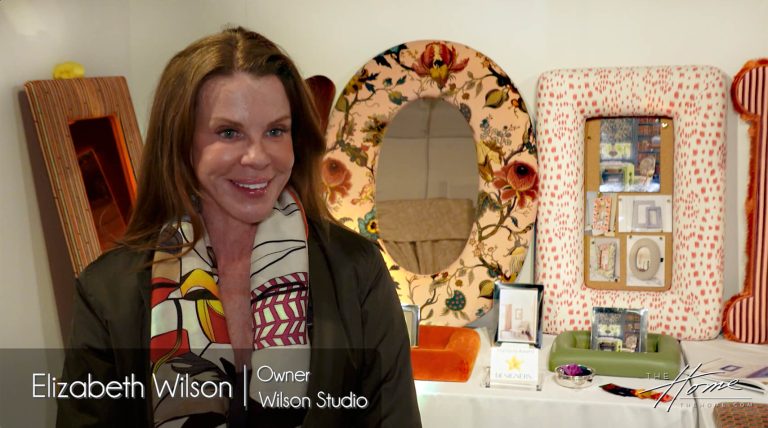 image of woman with brown hair standing by custom designer mirrors with colorful fabric-upholstered frames